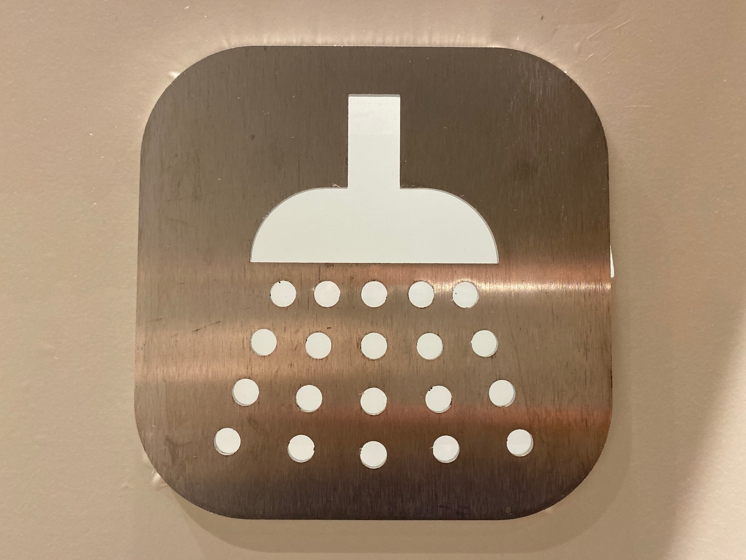 a metal sign with a shower head cut out