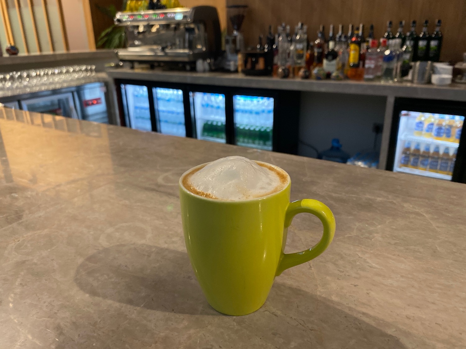 a green mug with a foamy drink on a counter