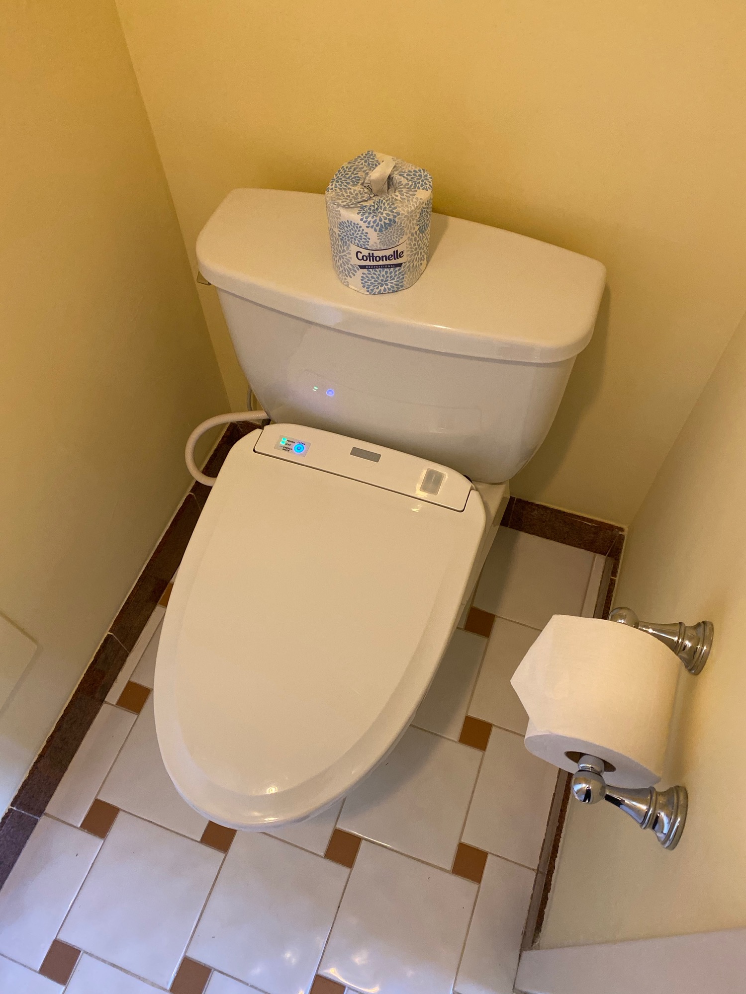 a toilet with a roll of toilet paper on the tank