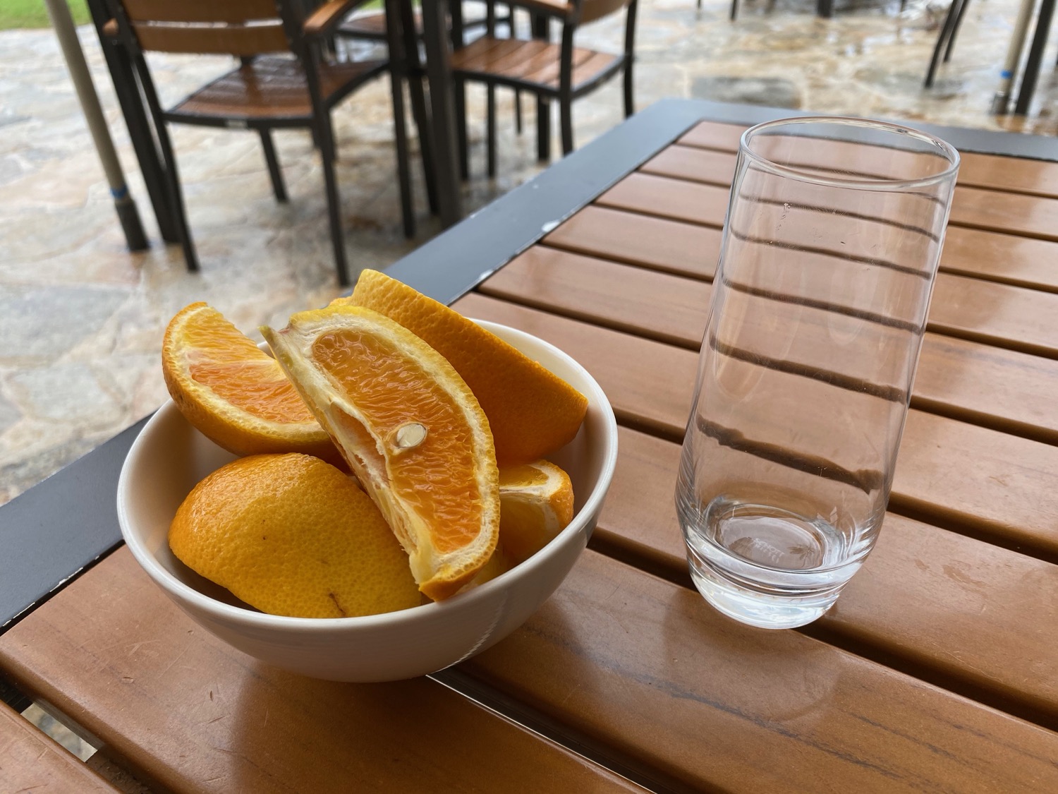 a bowl of oranges and a glass on a table
