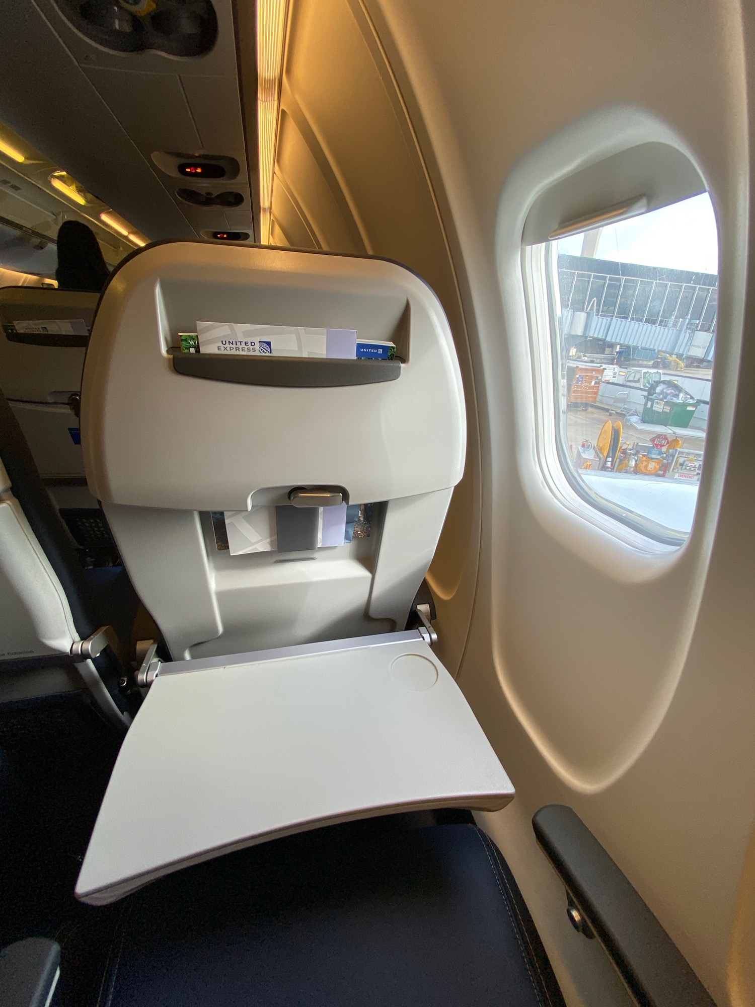 an airplane seat with a shelf and a window