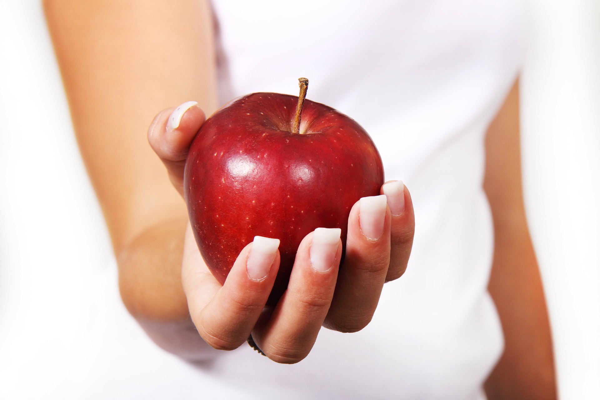 a hand holding a red apple