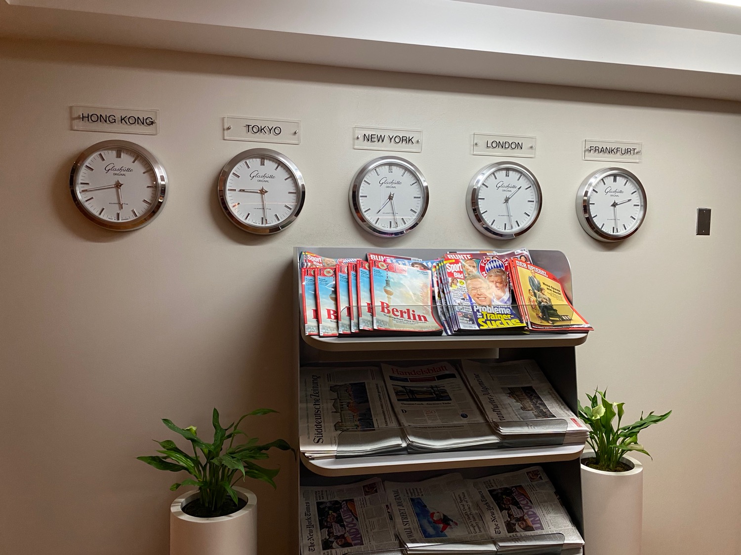 a shelf with newspapers and clocks on the wall