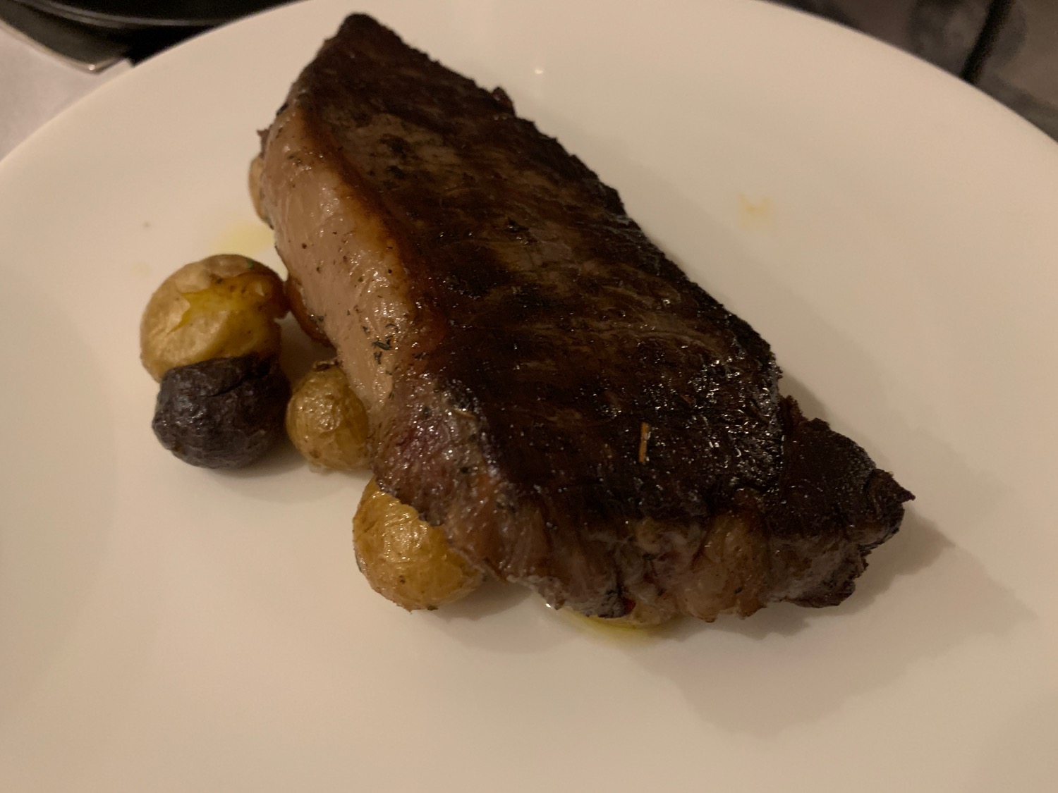 a piece of steak with potatoes on a white plate