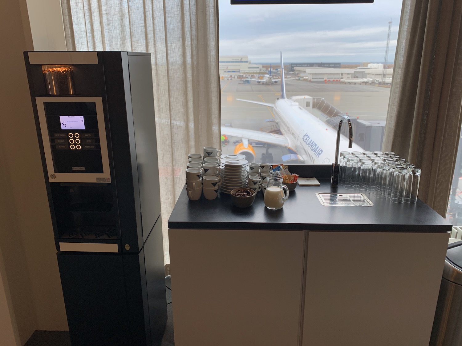 a coffee machine and a table with cups and glasses