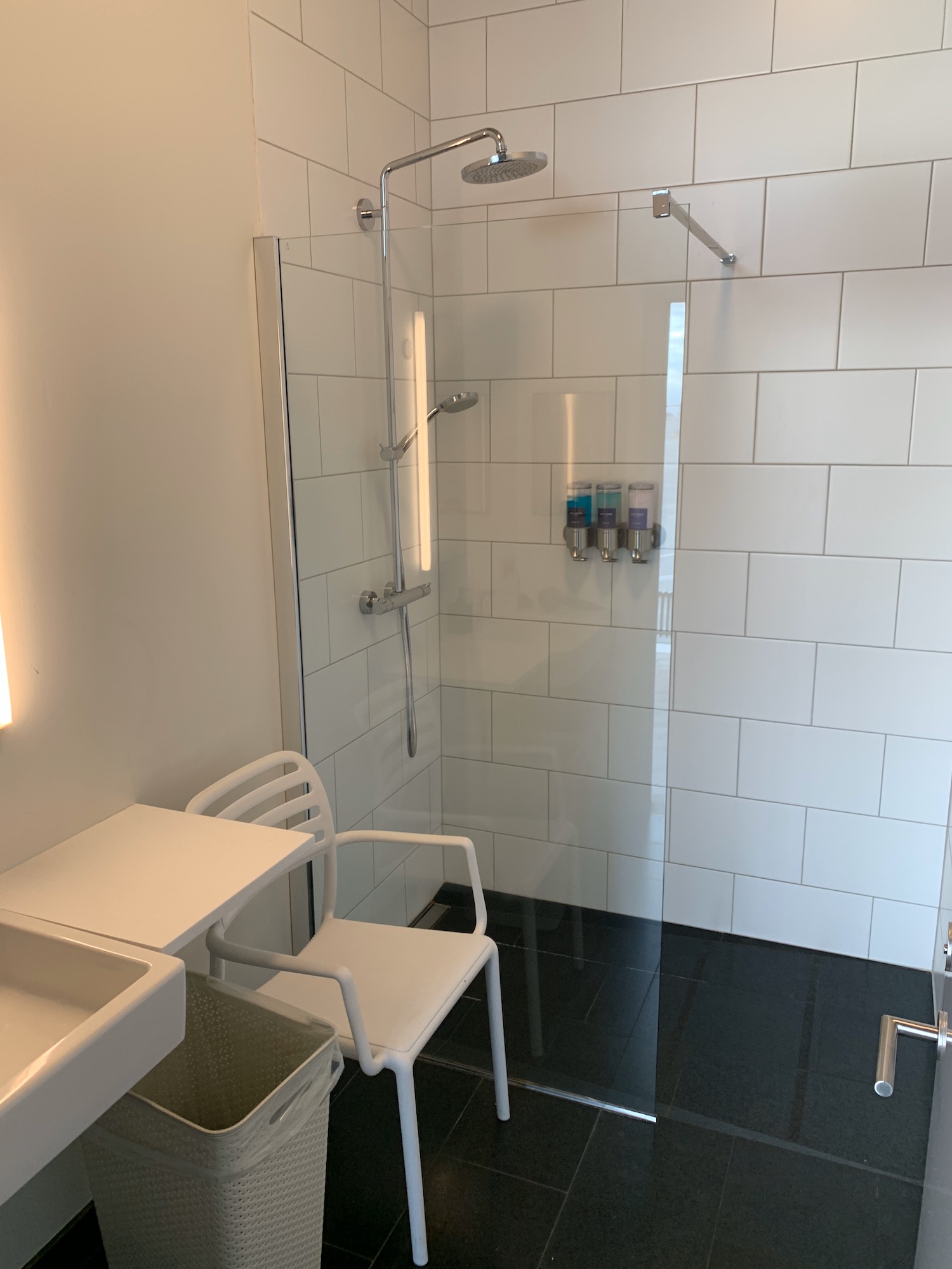 a shower with a sink and a chair