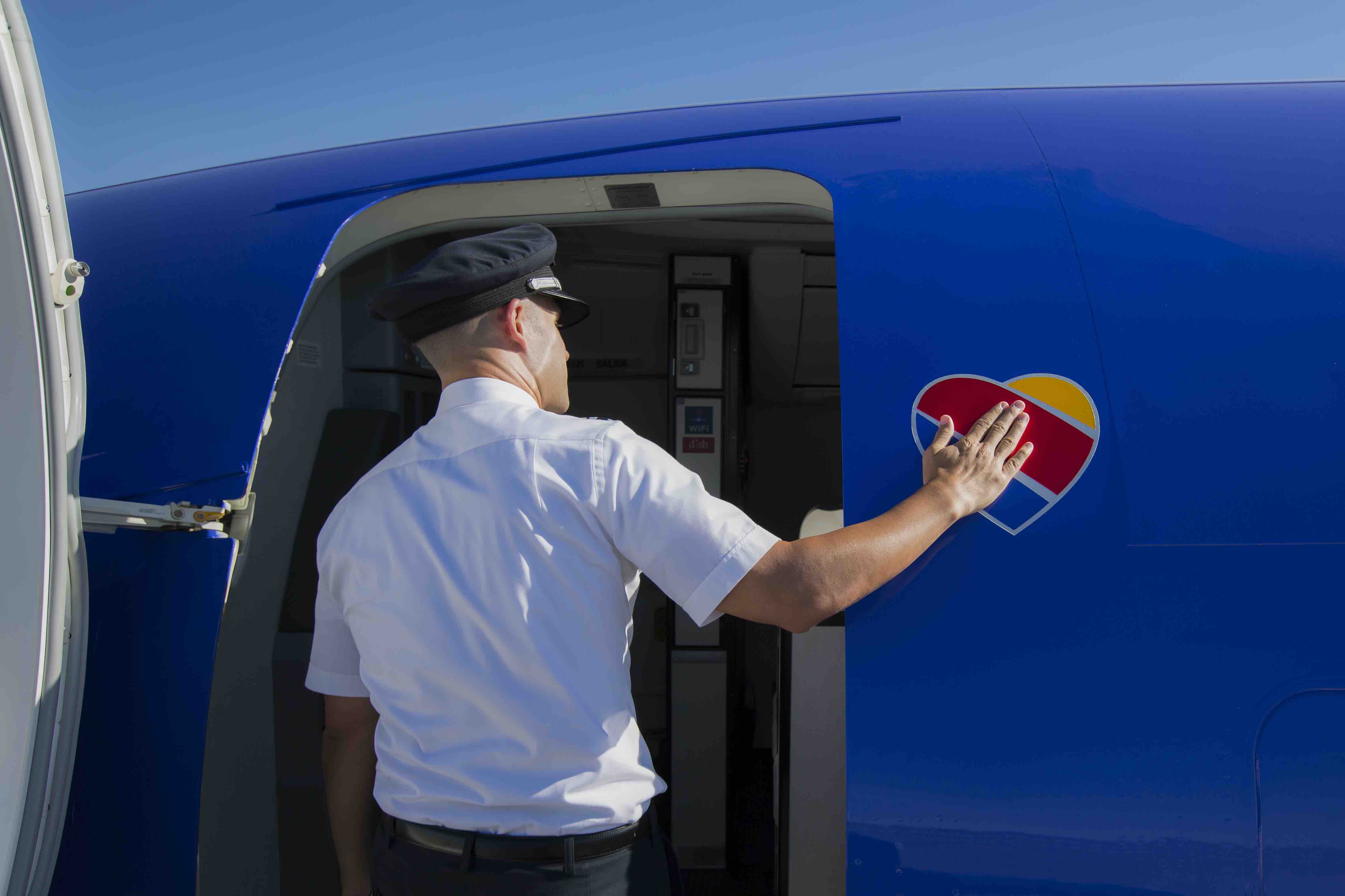 a man in a uniform opening a door of a blue plane