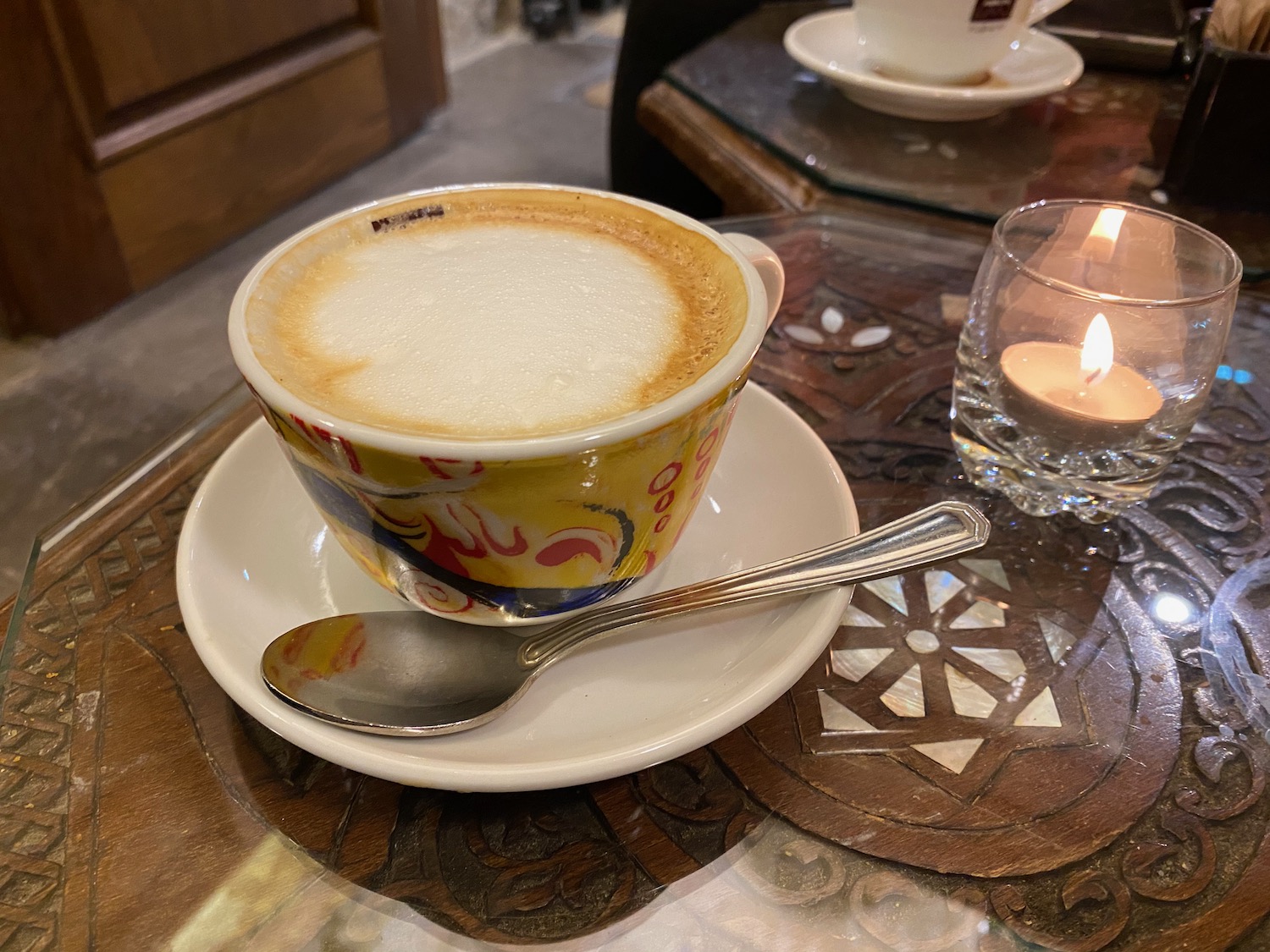 a cup of coffee with a spoon and a candle on a table