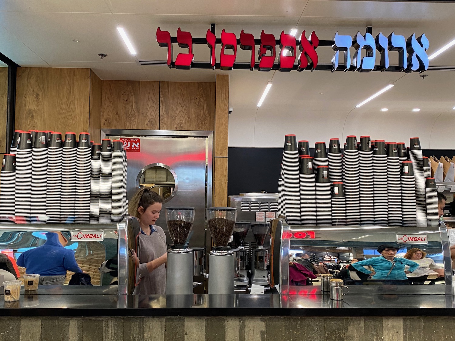 a woman behind a counter with a group of stacks of coffee cups