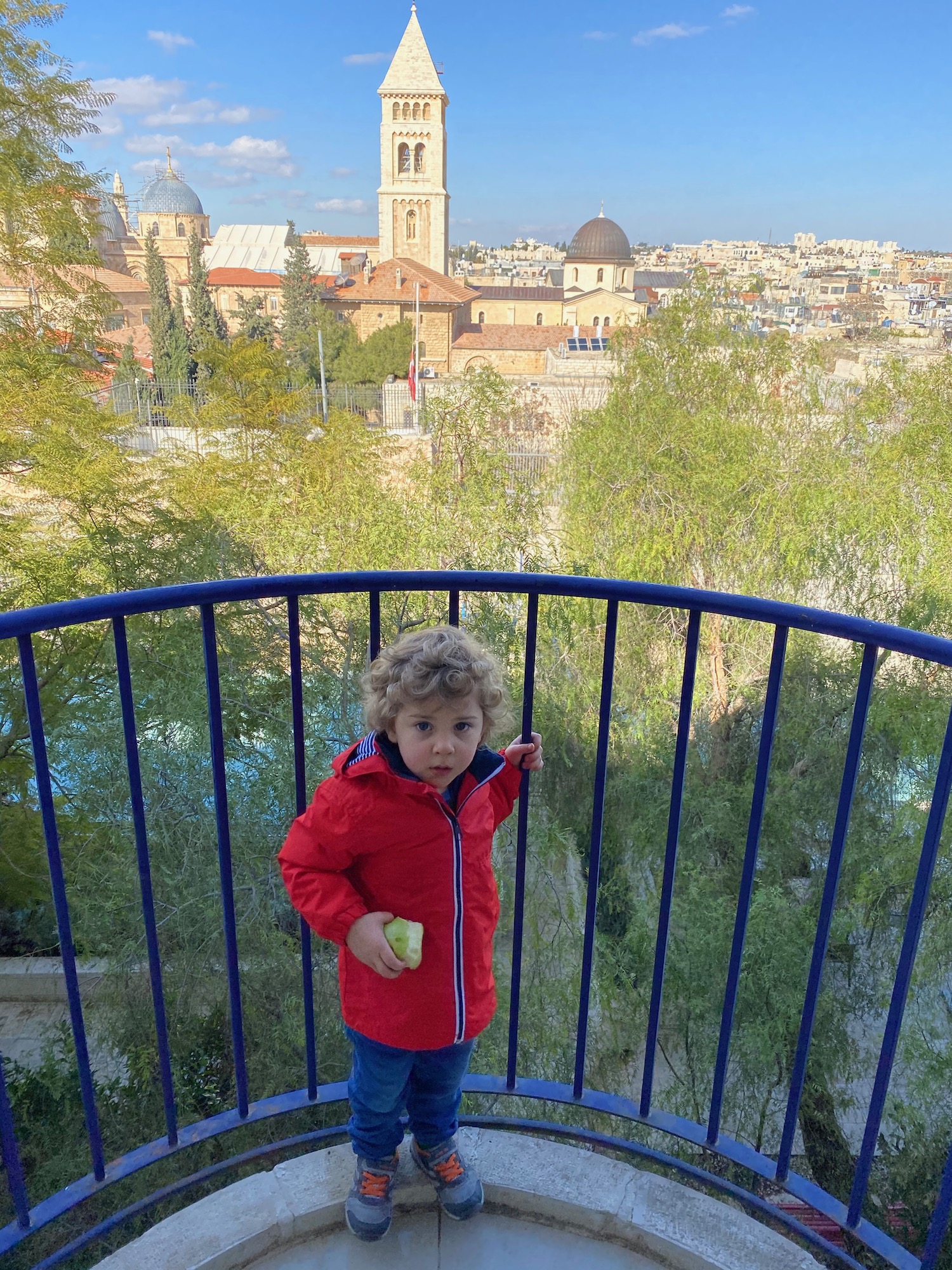 a child standing on a balcony with a city in the background
