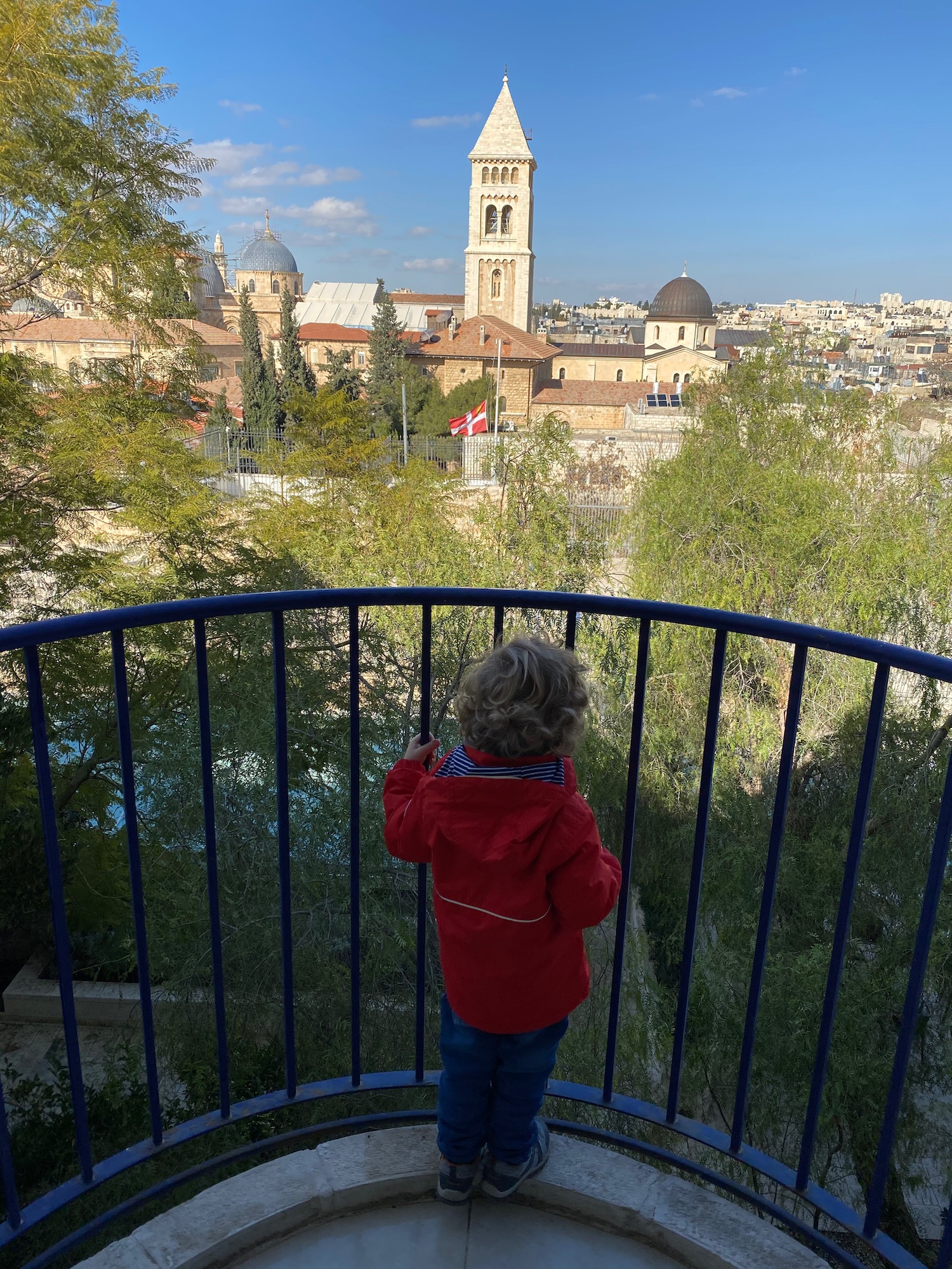 a child standing on a balcony overlooking a city