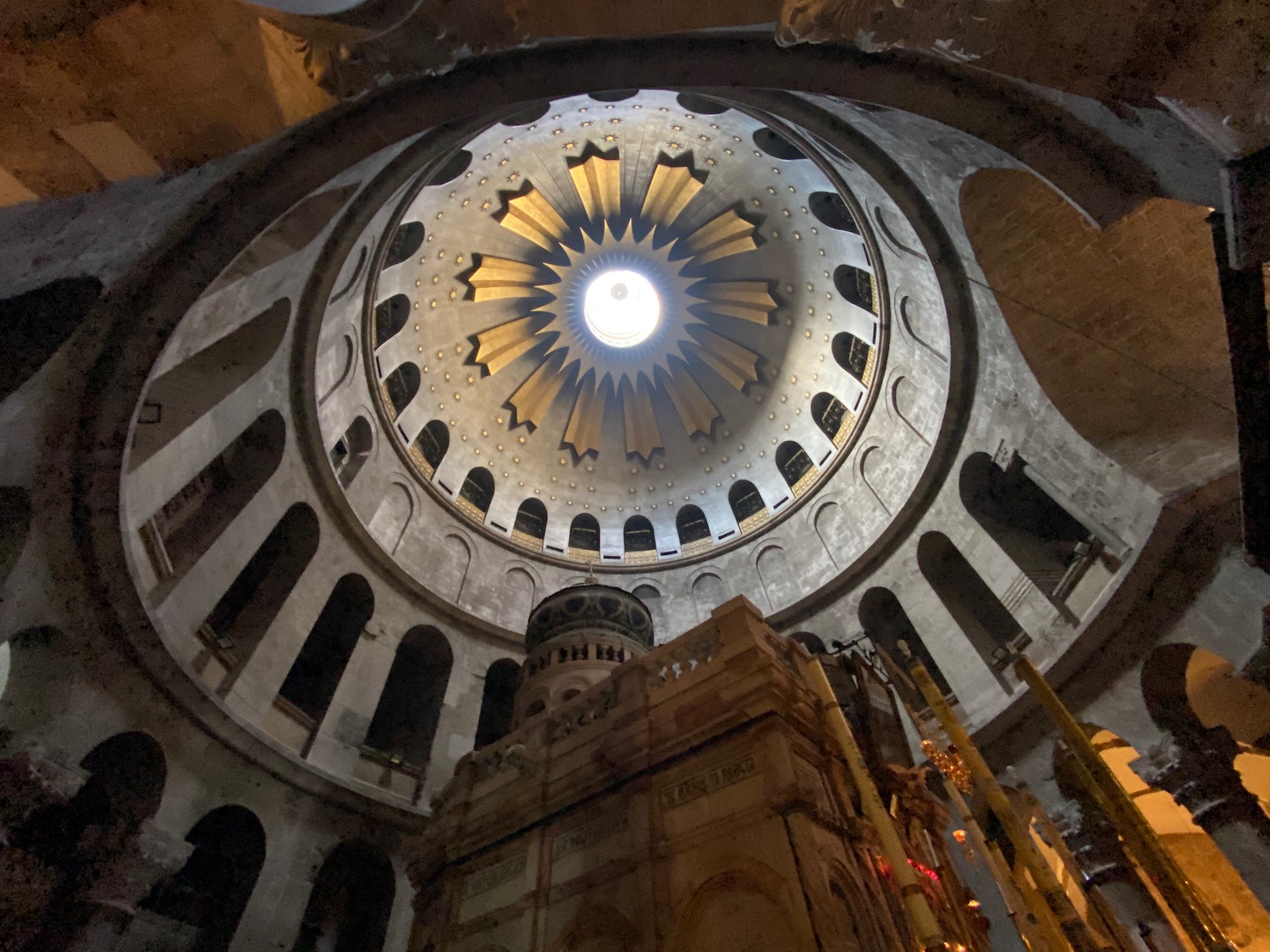 a circular ceiling with a light in the middle with Church of the Holy Sepulchre in the background