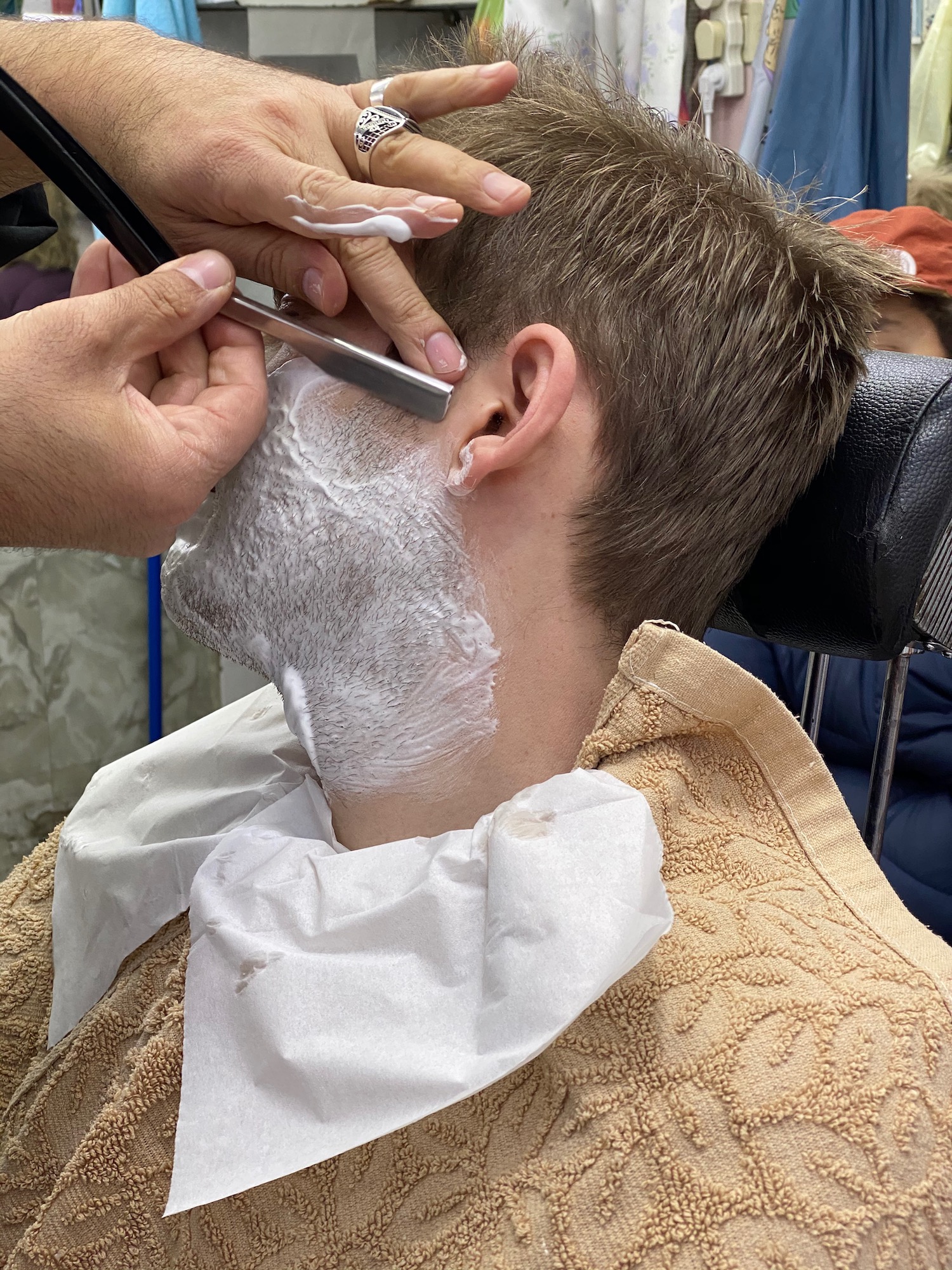 a person shaving a man's head