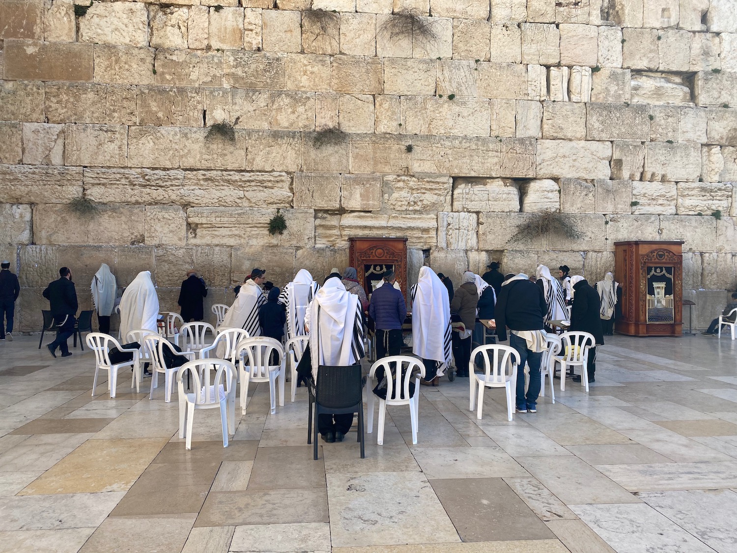 a group of people in white robes with Western Wall in the background