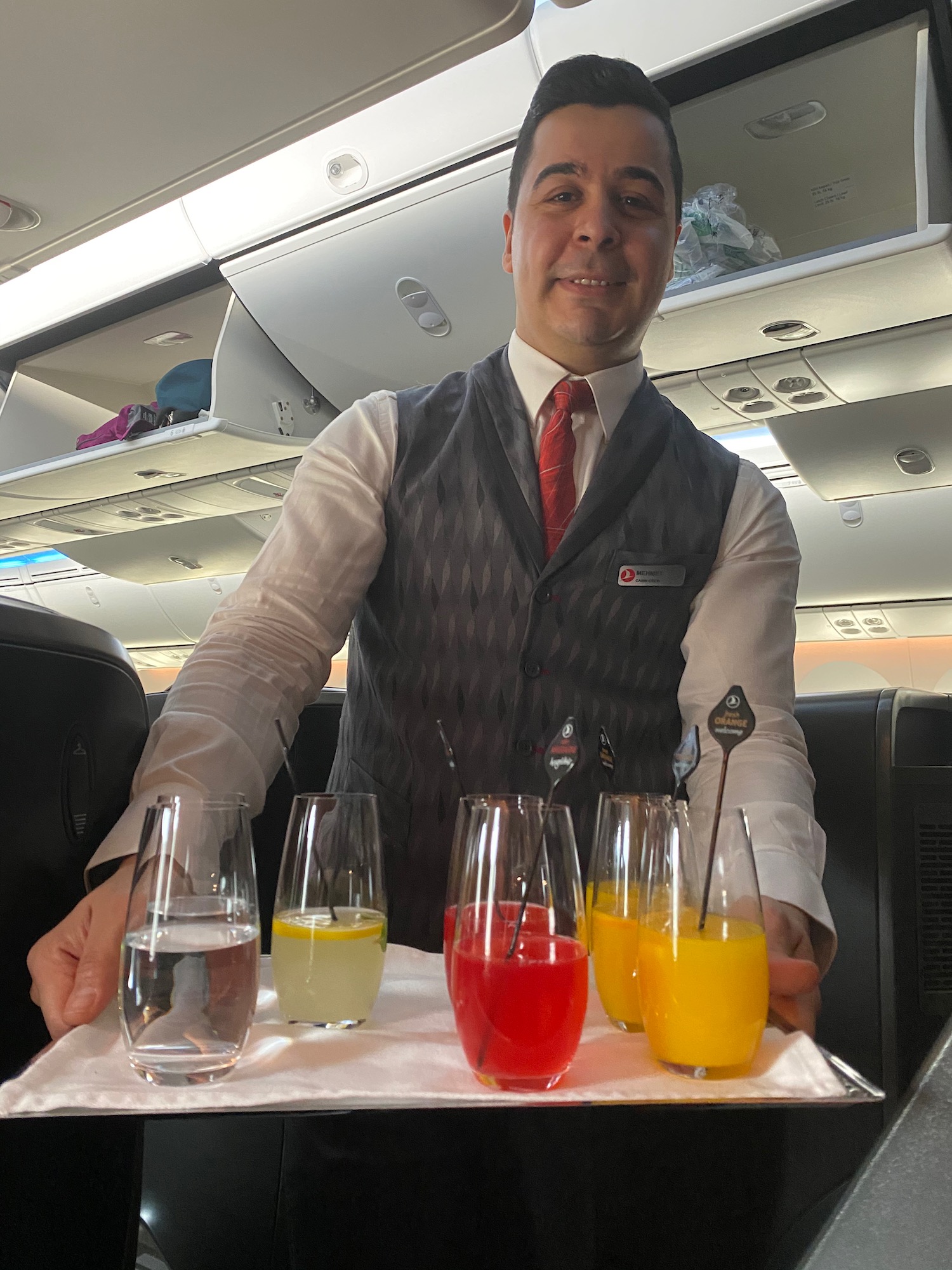 a man in a vest and tie holding a tray of drinks