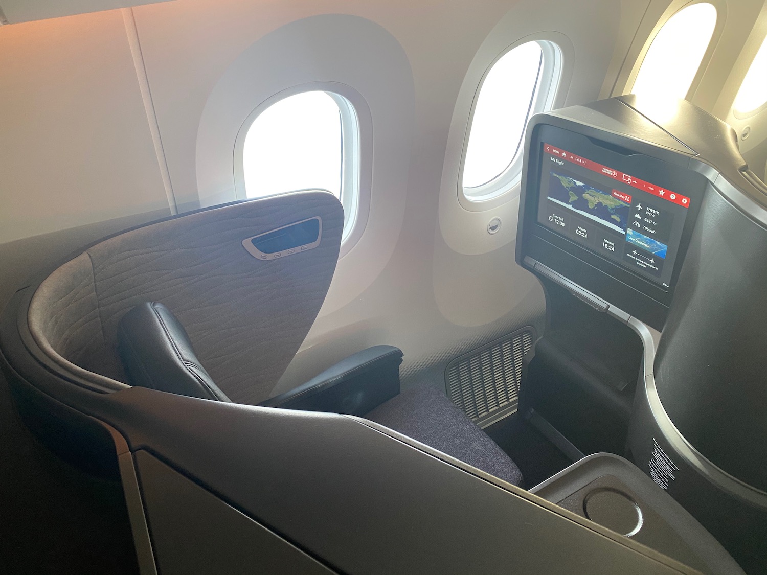 a seat in an airplane with a screen and windows