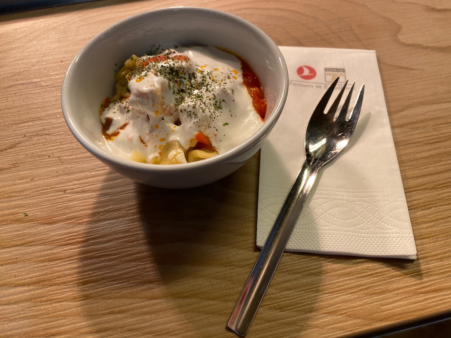 a bowl of food with a fork and napkin on a table