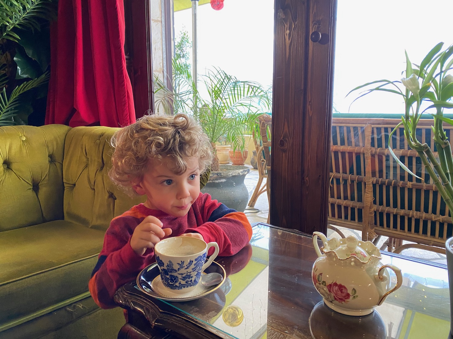 a child sitting at a table with a tea cup and saucer
