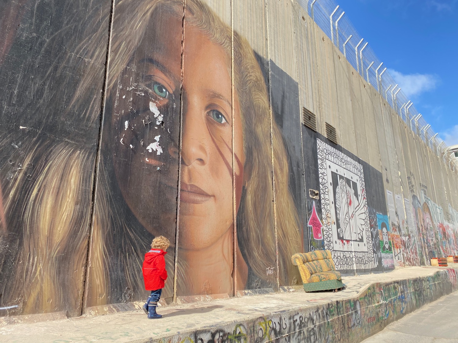 a child standing in front of a wall with graffiti
