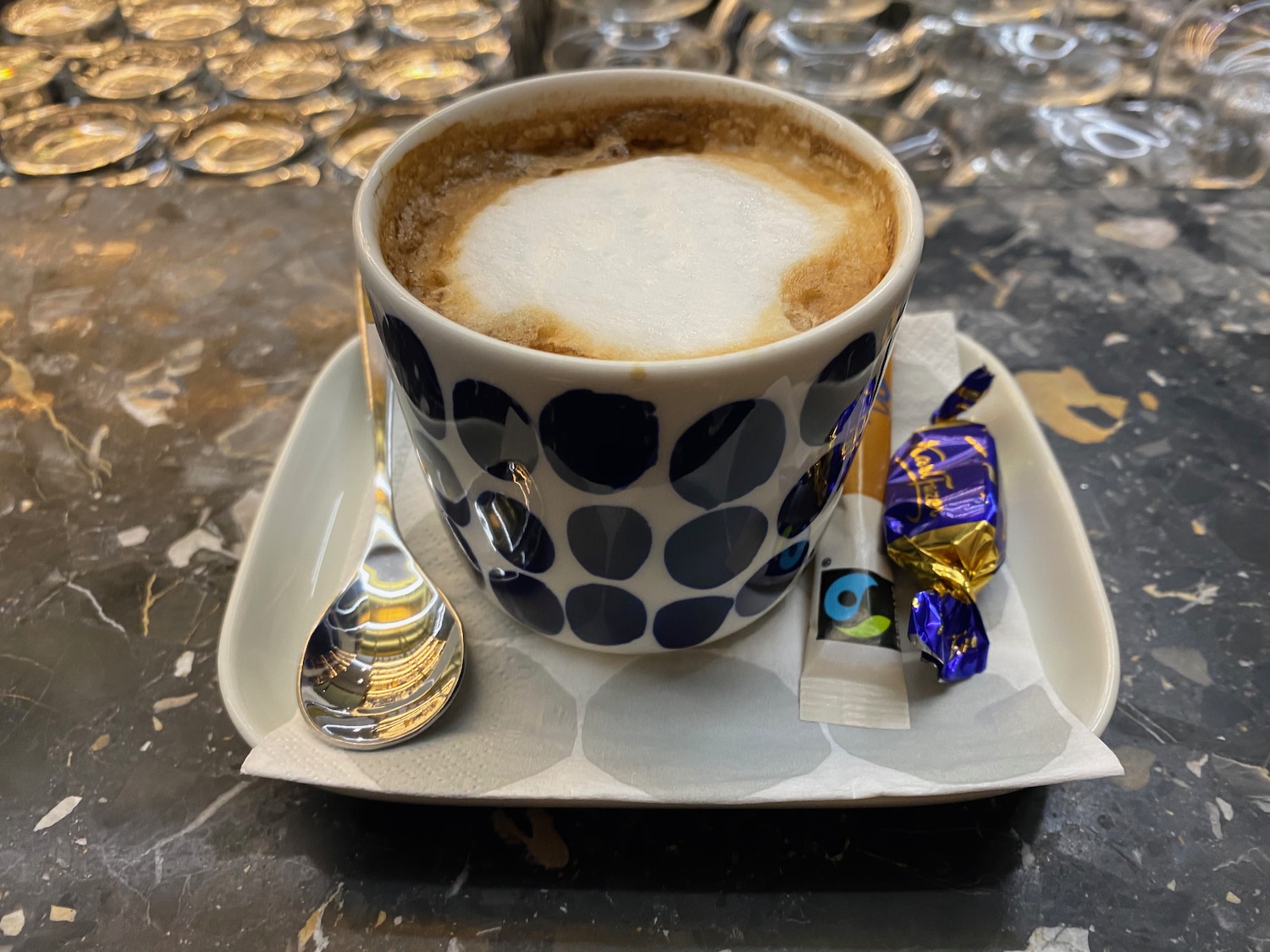 a cup of coffee with a spoon and candy on a plate