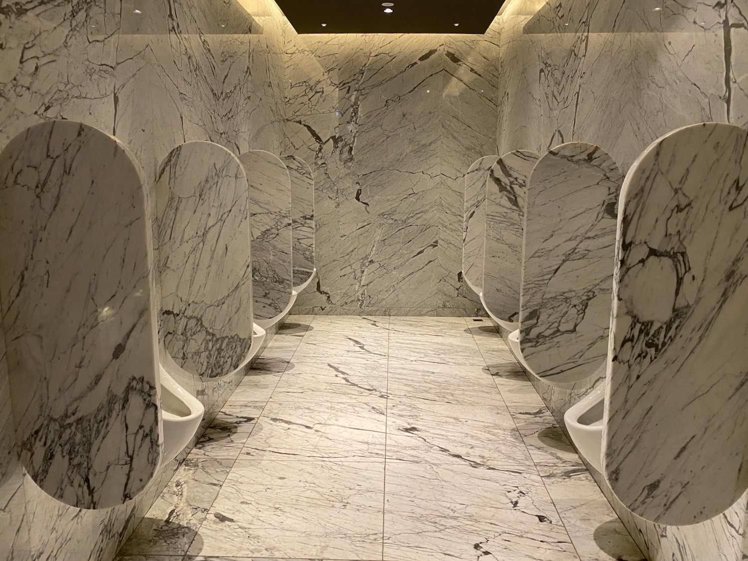 a bathroom with marble walls and urinals
