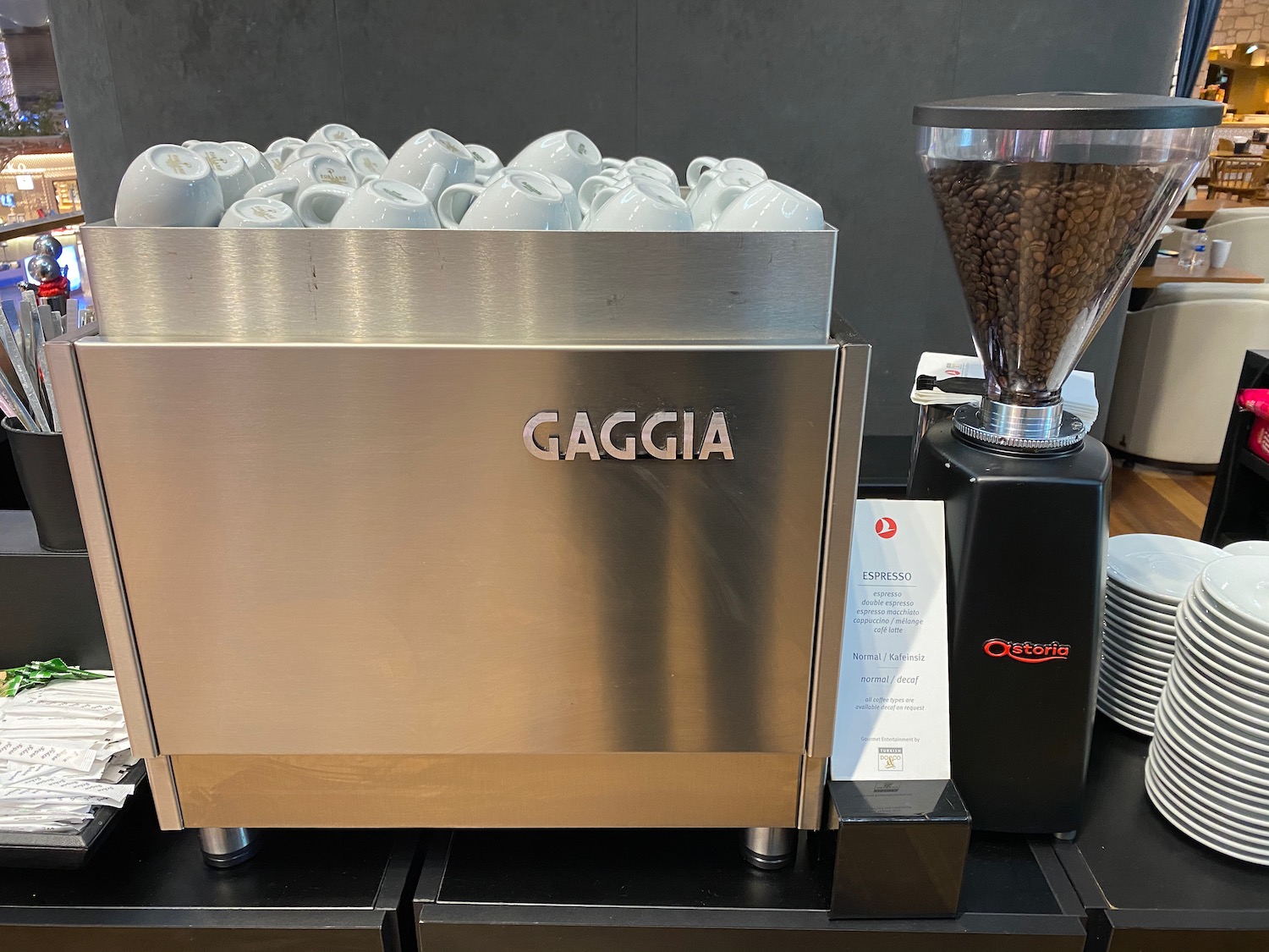 a machine with coffee beans and white cups