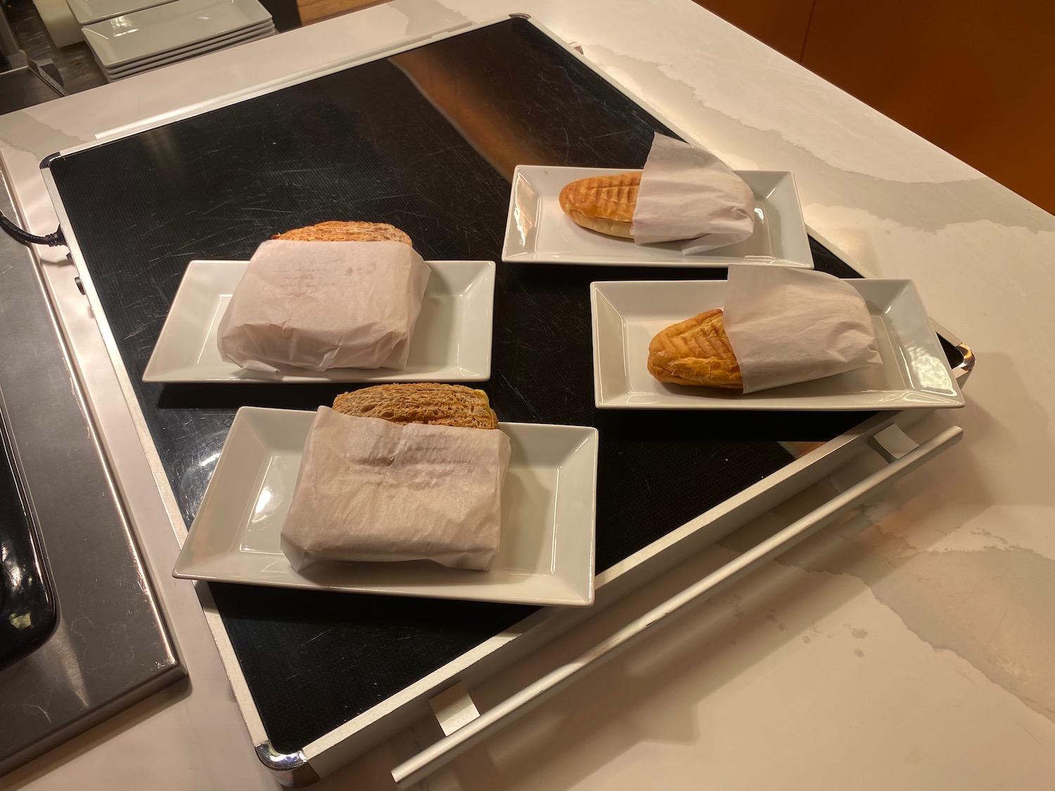a group of white rectangular plates with food wrapped in paper